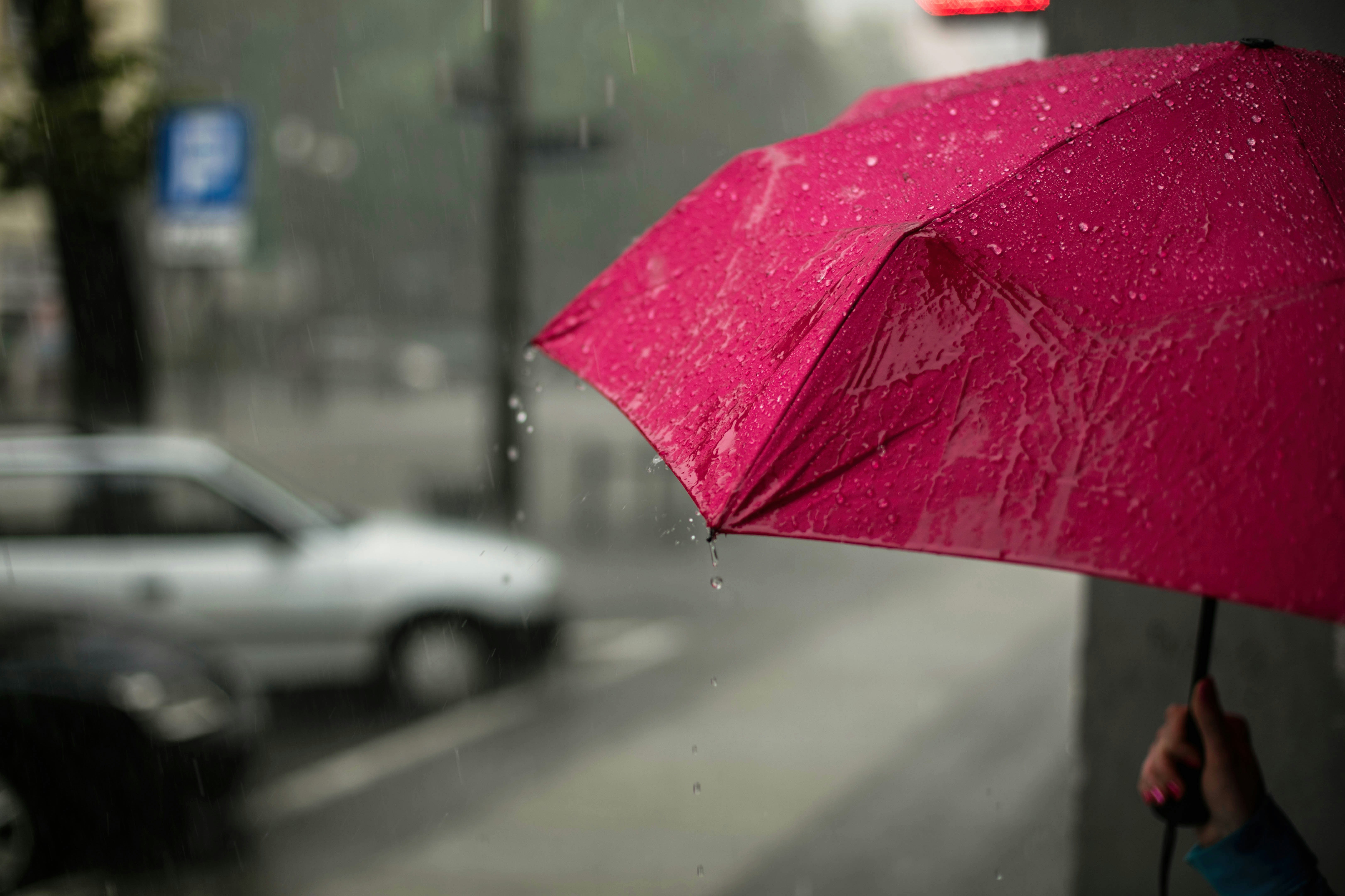 Pink umbrella with rain water falling on it