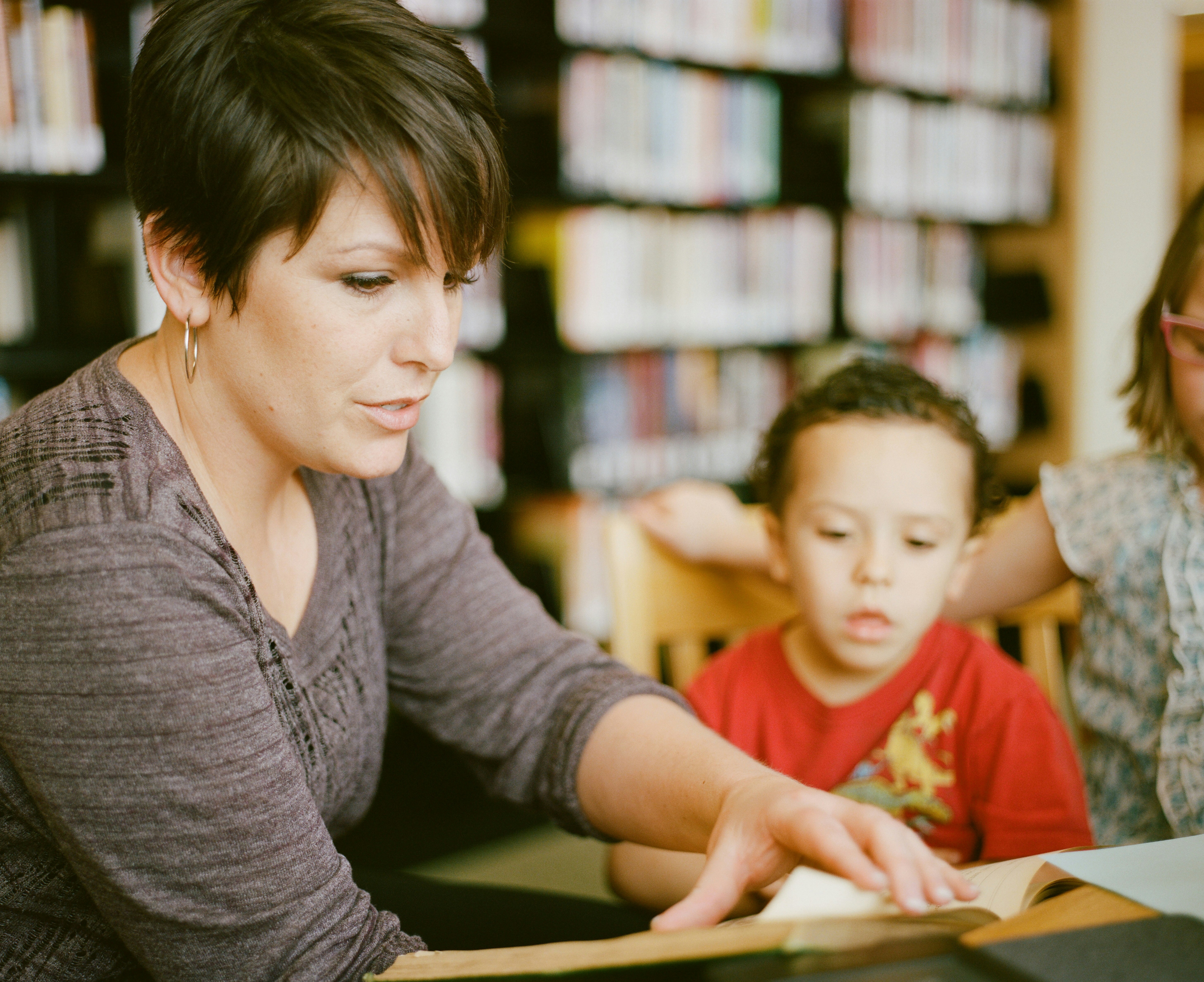 Teacher seated with her students teaching them from a book