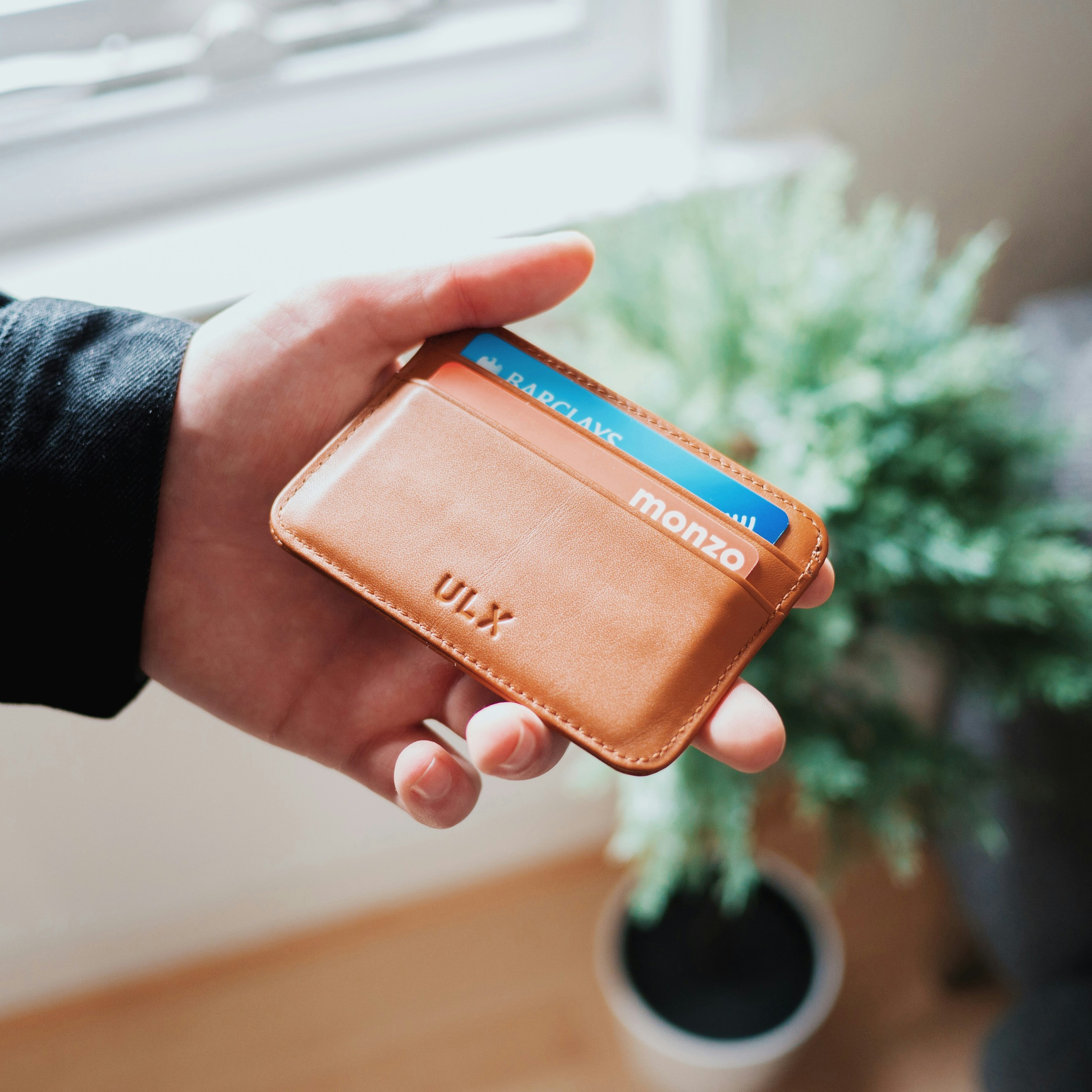 Man holding brown wallet carrying credit cards