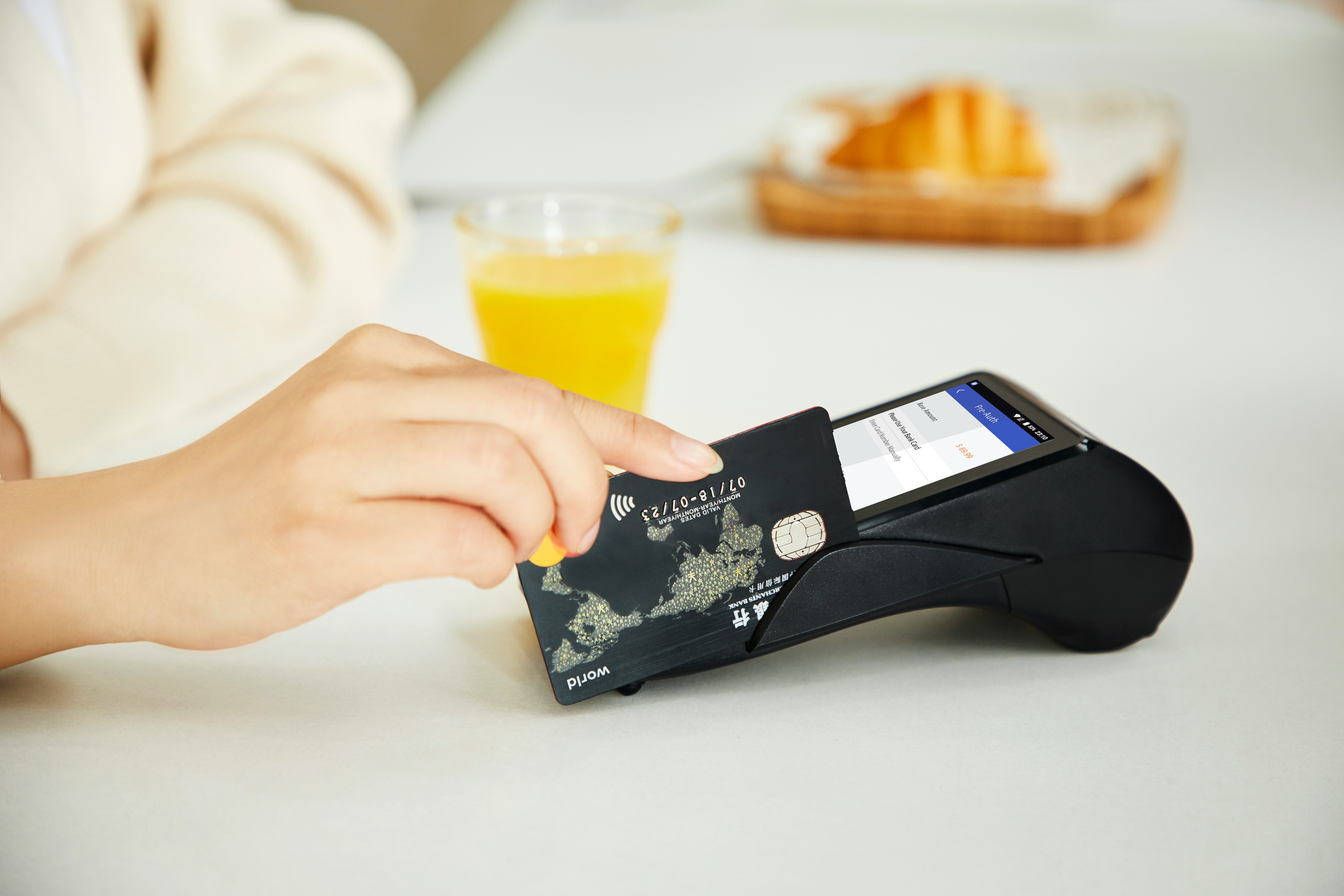 Person seated at an eatery swiping credit card on a card reader machine