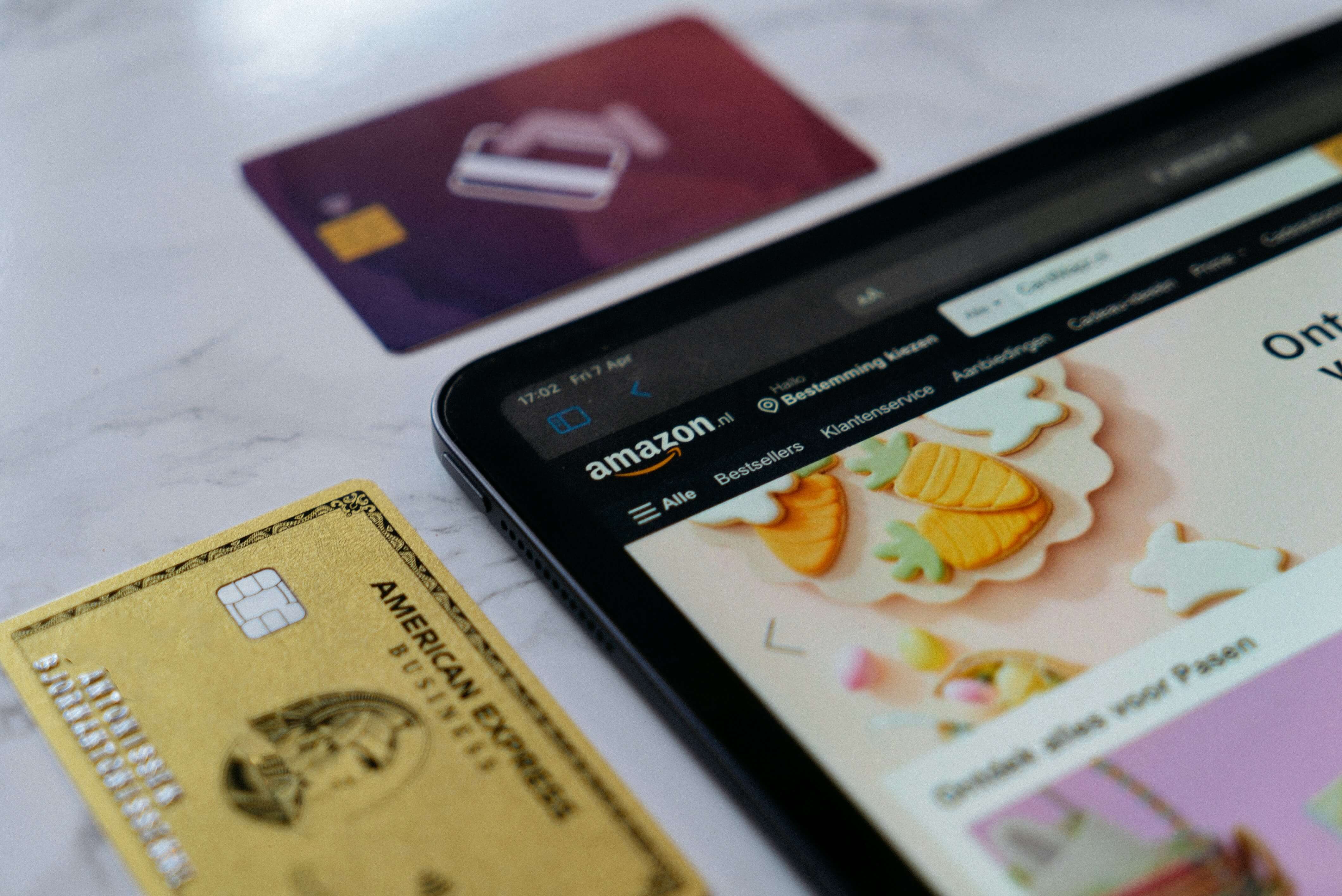 Credit cards lying next to tablet with the Amazon website open