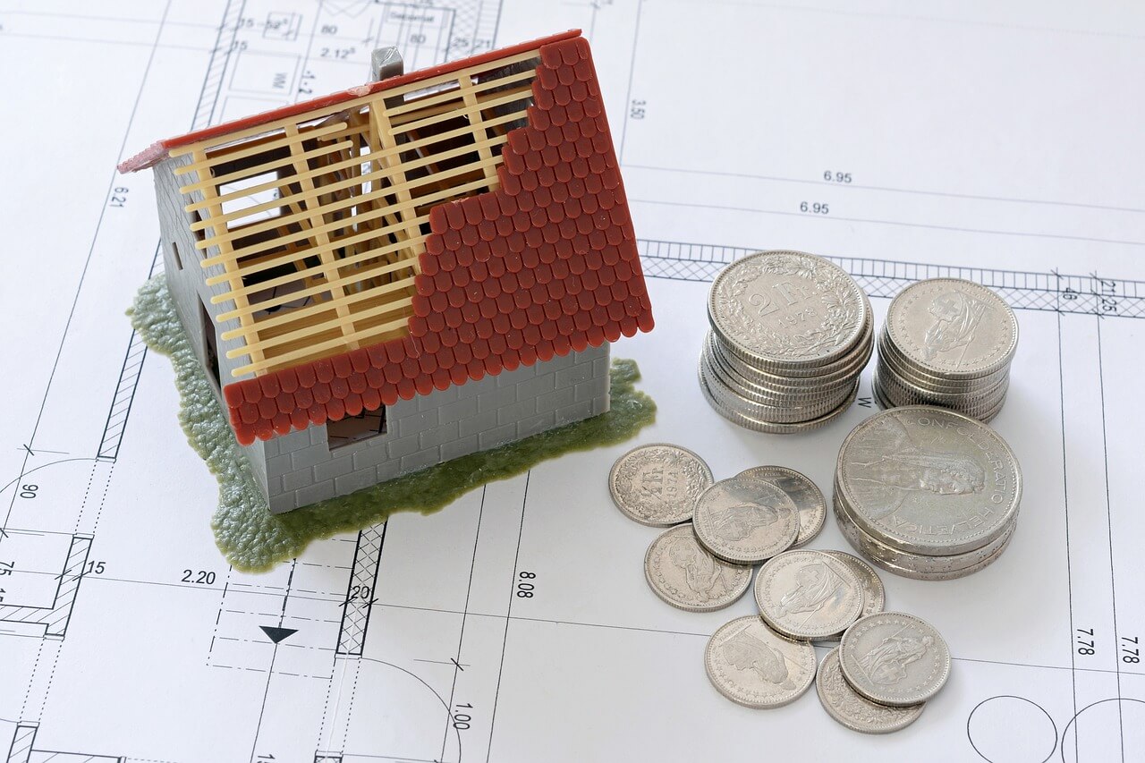 Tiny house under construction with stacked coins beside it to symbolize credit building