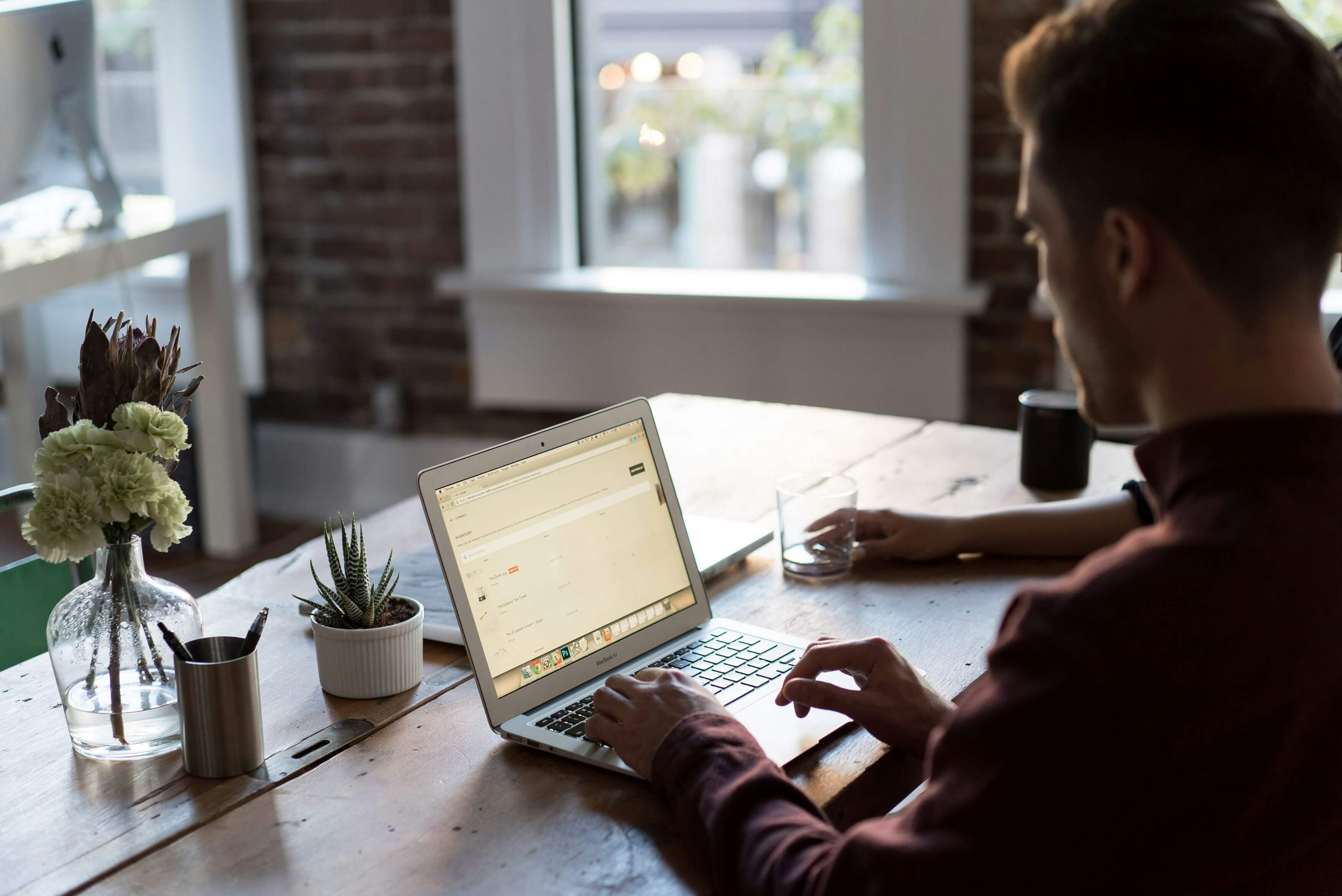 Man seated at table looking over his laptop