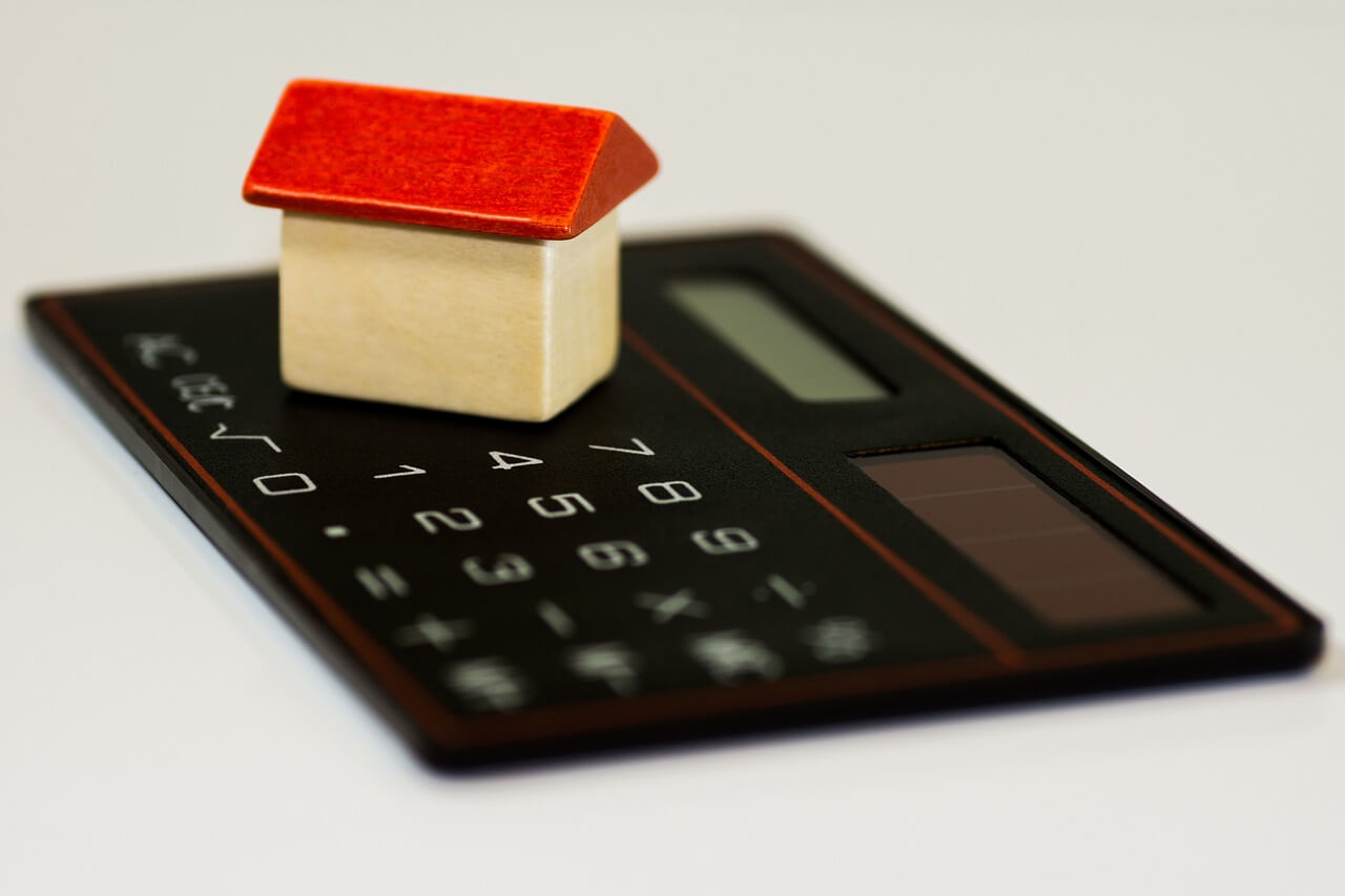 Toy house on a calculator symbolizing mortgage loan payment calculation.